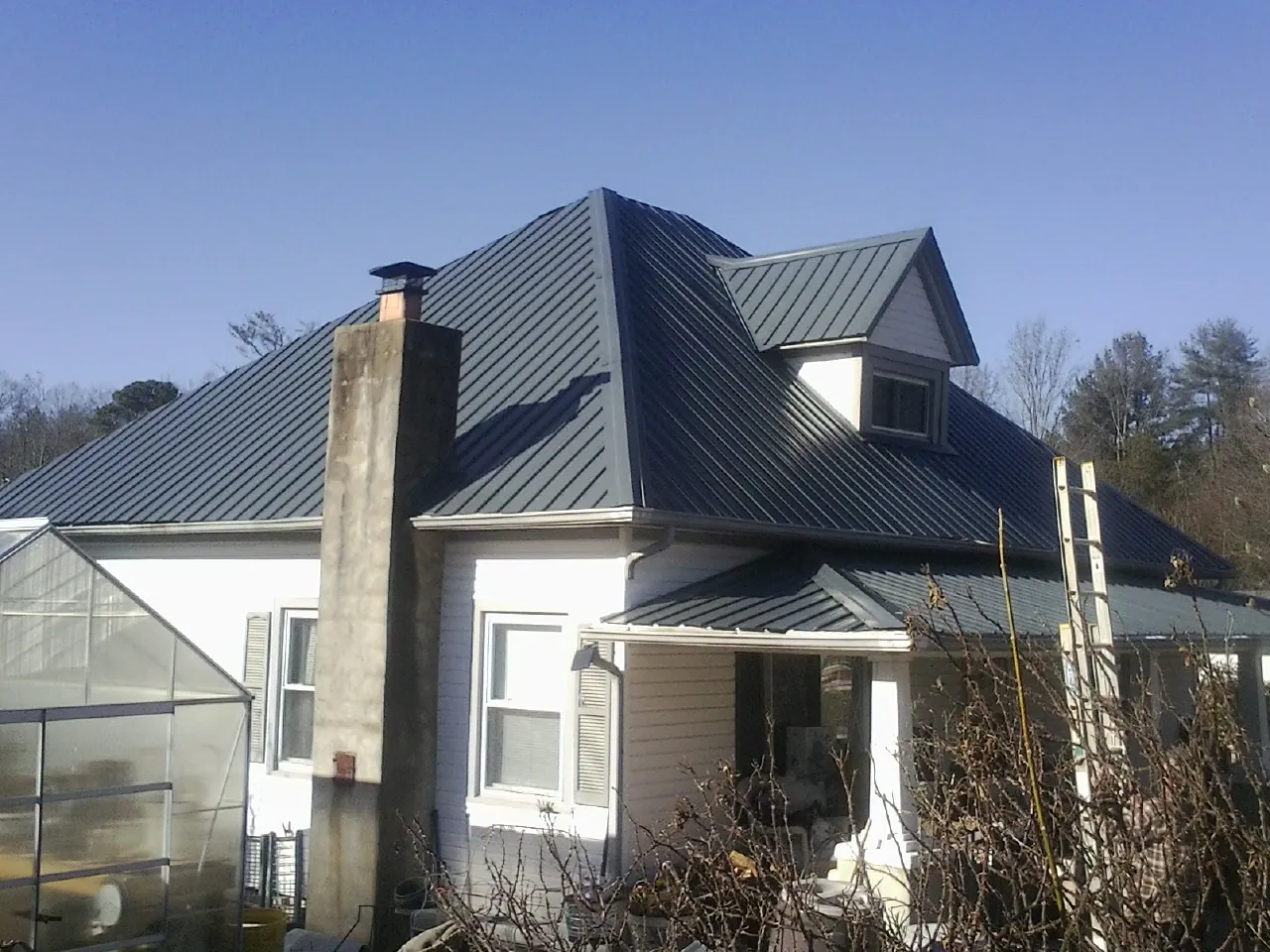 Dark blue standing seam metal roof on a white farmhouse with dormer — Slate & Tile Roof Repair by Roofing Brothers in Amarillo