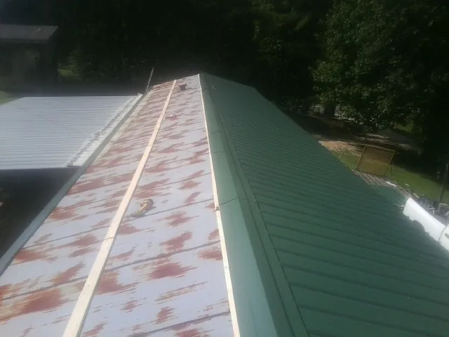Old rusted panels beside newly installed green metal roofing — Wind Damage Roof Repair by Roofing Brothers in Amarillo