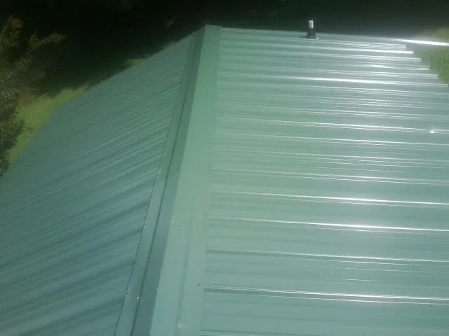 New green metal panels meeting at the ridge of a roof — Flat Roof Repair work by our crew in Amarillo