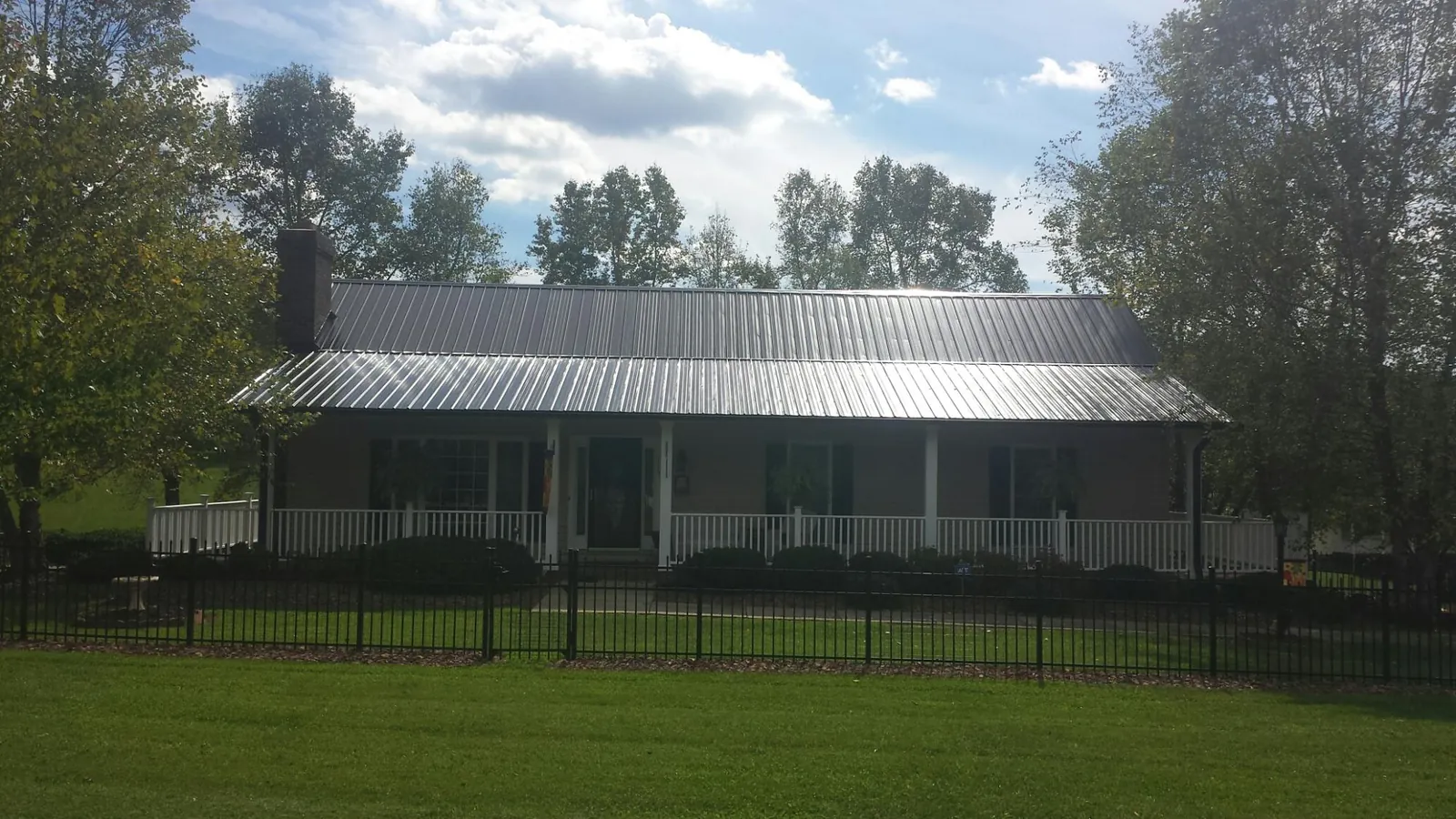 Gray metal roof on a brick ranch with a full width front porch — Gutter Guard Installation work by our crew in Amarillo